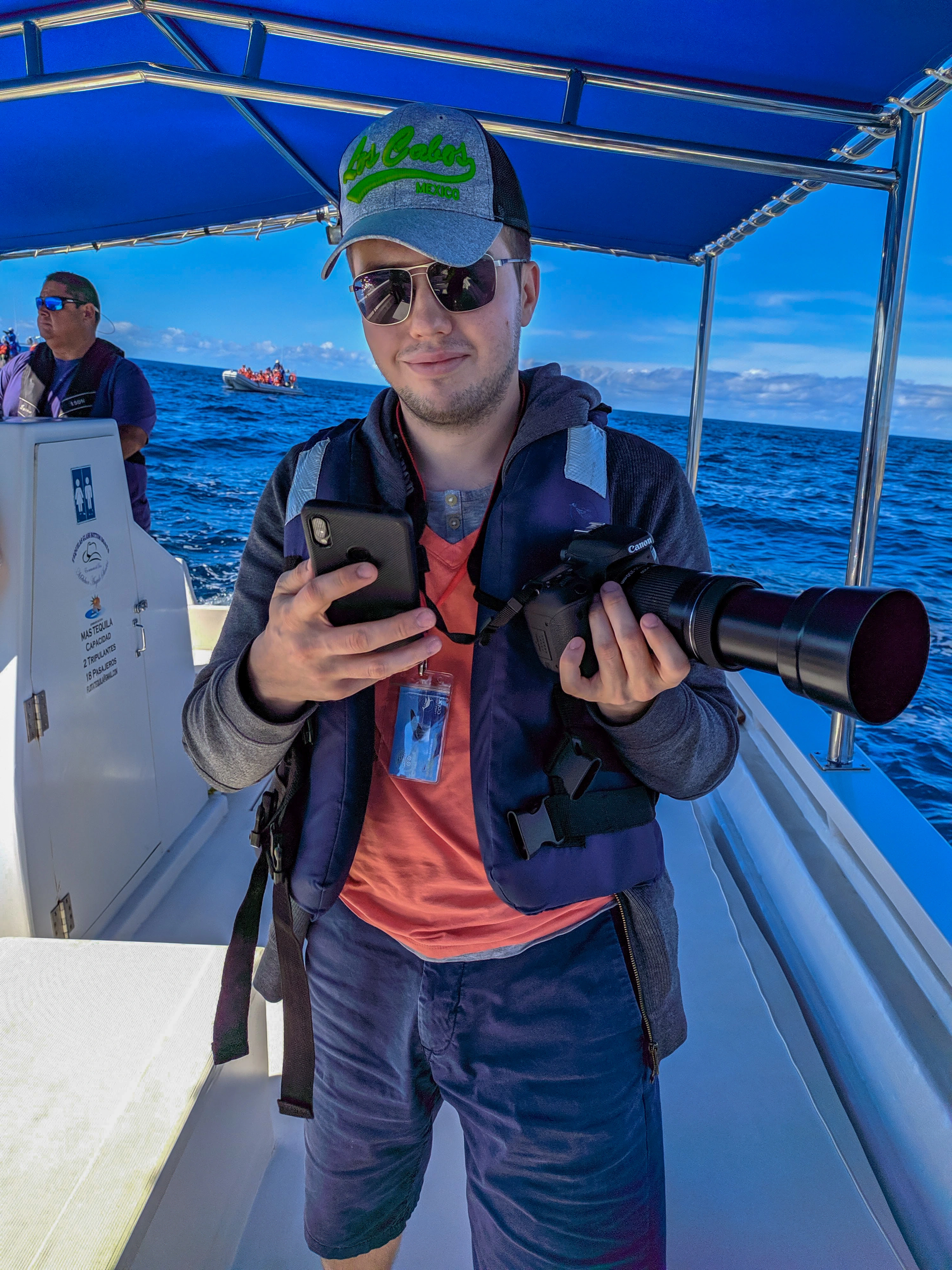 Nikita on a boat with a DSLR and phone